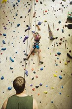 Caucasian man belaying climber at indoor rock wall