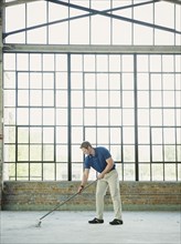 Caucasian businessman sweeping warehouse floor