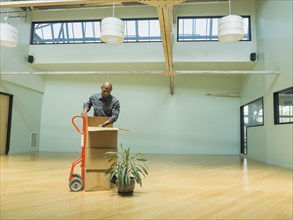Black businessman unpacking cardboard boxes in empty office