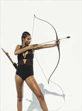 Mixed race woman aiming bow and arrow