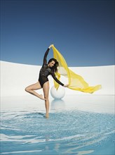 Caucasian woman dancing with fabric on water surface