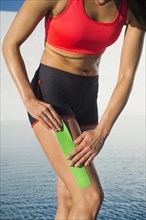 Caucasian athlete taping thigh near swimming pool