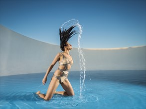 Caucasian woman tossing hair on swimming pool