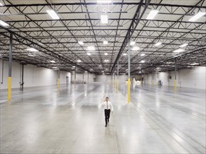 Caucasian businessman walking in empty warehouse