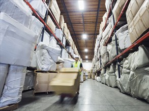 Blurred view of Caucasian worker wheeling cardboard box in warehouse