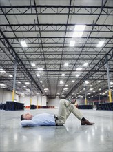 Caucasian businessman laying on floor in empty warehouse