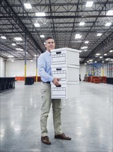 Caucasian businessman carrying boxes in empty warehouse