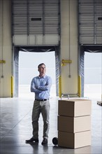 Caucasian businessman standing near cardboard boxes in warehouse