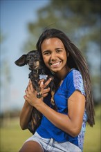 Mixed race girl hugging dog outdoors