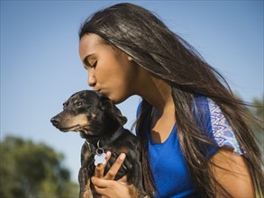 Mixed race girl kissing dog outdoors