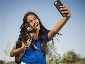 Mixed race girl taking selfie with dog