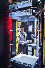 Hispanic technician using computer in server room