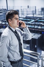 Hispanic businessman talking on cell phone on balcony over server room
