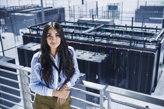 Mixed race businesswoman smiling on balcony over server room