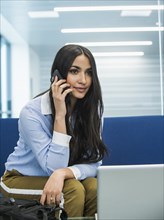 Mixed race businesswoman talking on cell phone in office lobby