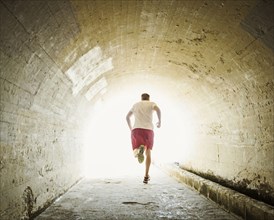 Caucasian man jogging in tunnel