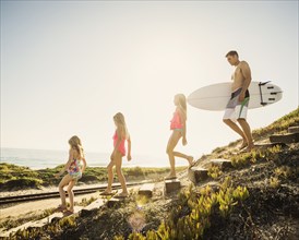 Caucasian father and daughters walking on beach