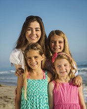 Caucasian mother and daughters smiling on beach