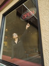 Hispanic business owner using open sign