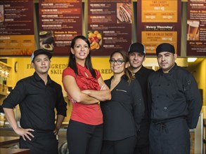 Hispanic business owner and employees smiling in cafe
