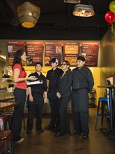 Hispanic business owner and employees talking in cafe