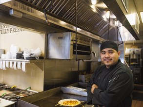 Hispanic chef smiling in kitchen