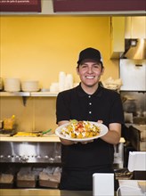 Hispanic server holding food in cafe