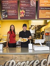 Hispanic server and businesswoman smiling in cafe