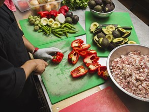 Hispanic chef cutting vegetables in kitchen