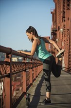 Caucasian woman stretching on urban bridge
