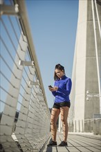 Caucasian woman using cell phone on urban bridge