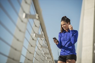 Caucasian woman using cell phone on urban bridge