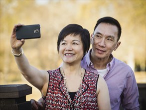 Older Chinese couple taking selfie outdoors