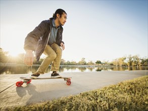 Chinese man skateboarding in park