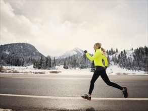 Caucasian woman running on snowy road