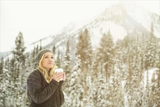 Caucasian woman drinking coffee in snow