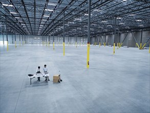 Architects using laptop and blueprint in empty warehouse