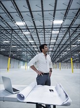 Indian architect standing with hands on hips in empty warehouse
