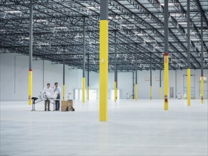 Architects using blueprint in empty warehouse