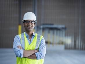 Smiling Indian worker in empty warehouse
