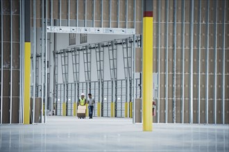 Workers with boxes on hand truck in empty warehouse