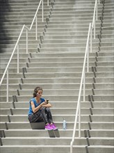Caucasian woman sitting on staircase texting on cell phone
