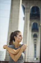 Caucasian woman stretching arms under overpass