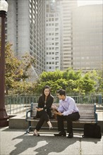 Chinese business people using technology on city bench