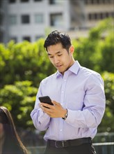 Chinese businessman texting on cell phone outdoors