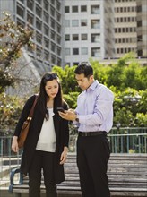 Chinese business people texting on cell phone near city bench