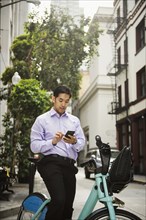 Chinese businessman on bicycle texting on cell phone