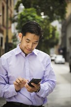 Chinese businessman texting on cell phone in city