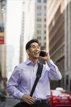 Chinese businessman talking on cell phone in city