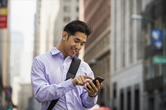Chinese businessman texting on cell phone in city